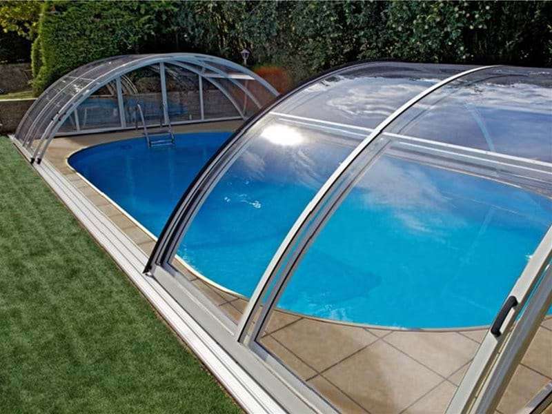 AQBox pool enclosure retracted open over a one piece swimming pool.