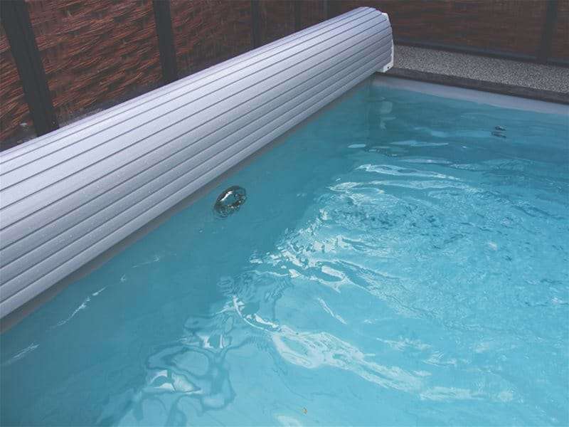automatic slatted pool cover open at the end of a one piece swimming pool.